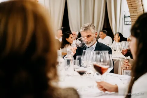 Tavolo di ospiti con calici di vino rosso